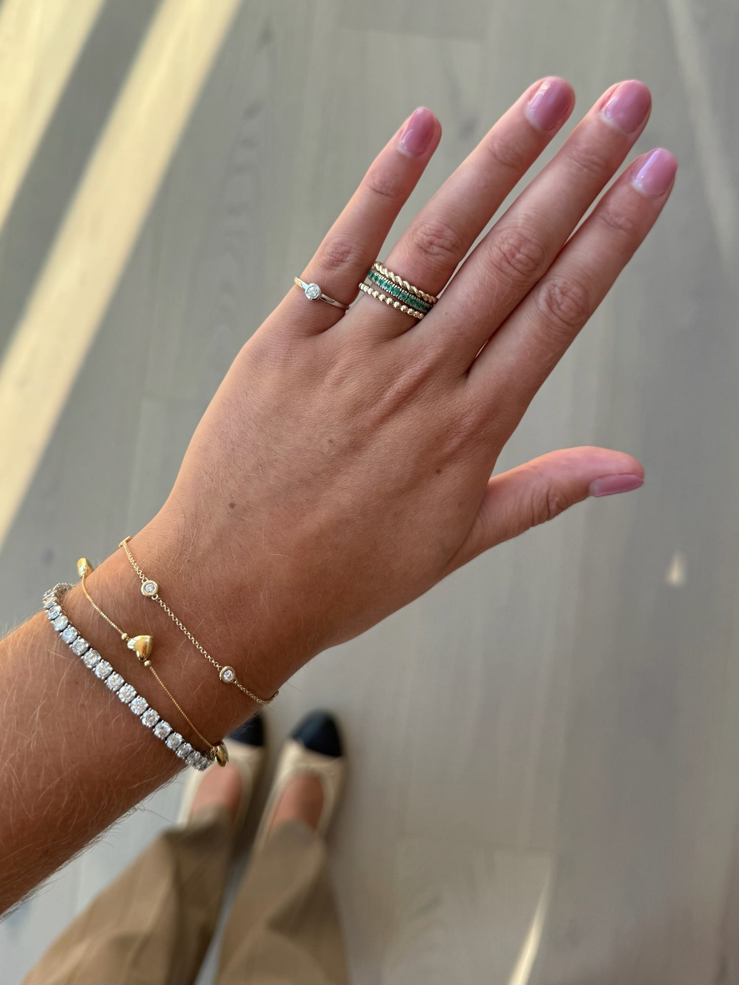 Hand wearing multiple rings and bracelets with a neutral background