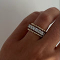 Hand wearing a bracelet and rope ring with a neutral background