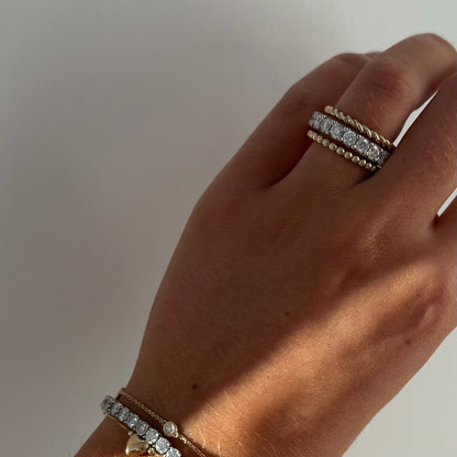 Hand wearing a bracelet and rope ring with a neutral background